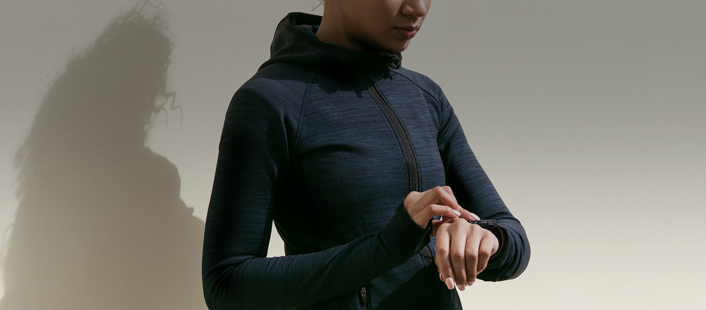 Woman is shown wearing athletic clothing and checking her smartwatch.