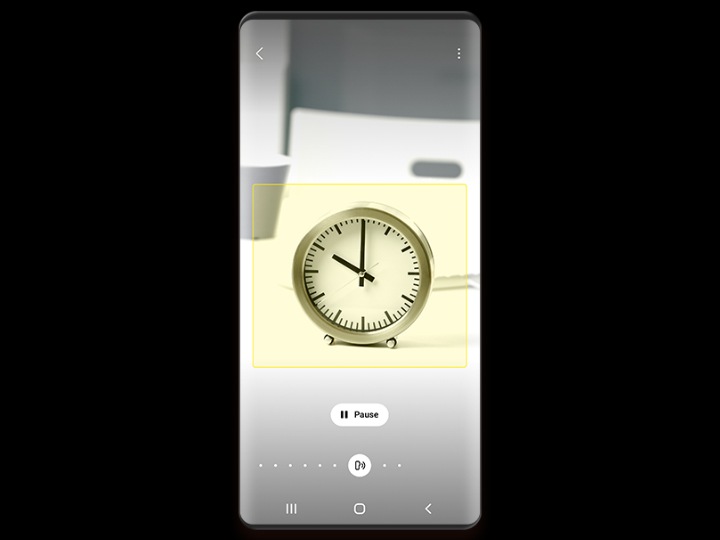 Een telefoonscherm toont een kleine bureauklok die door Bixby Vision wordt geïdentificeerd, met een pauzeknop onder het beeld.