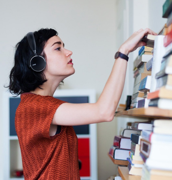 Een vrouw kijkt naar boeken. Ze draagt de AKG Y500 Wireless Headphones in zwart