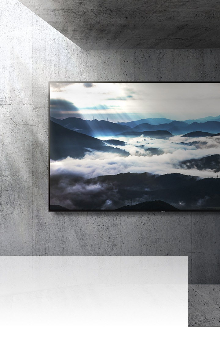 Een TV met een groot scherm hangt aan een betonnen muur een toont een natuurscène in 4K-resolutie. Van links schijnt de zon erop.