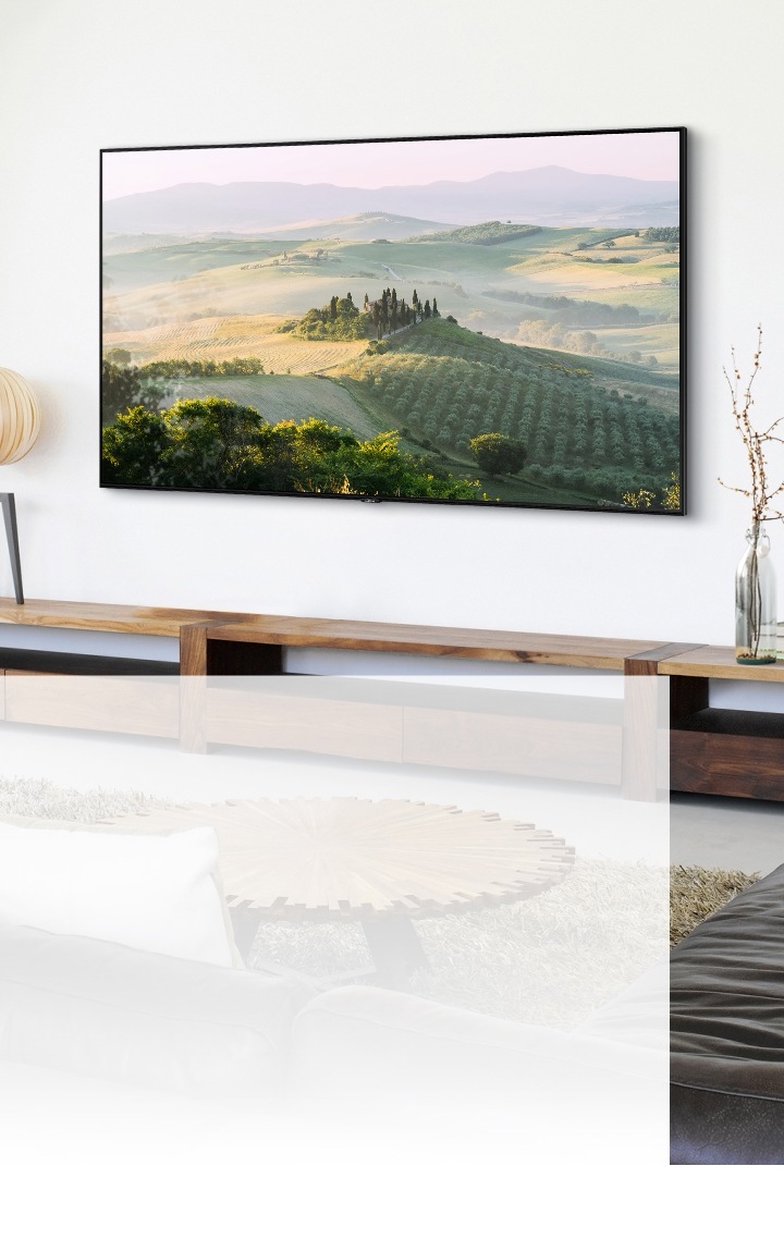 Een TV met een groot scherm hangt aan de muur en toont een natuurlandschap in een zonovergoten woonkamer.