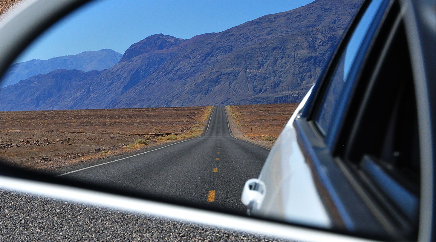 Gros plan du rétroviseur latéral d’une voiture reflétant un paysage montagneux