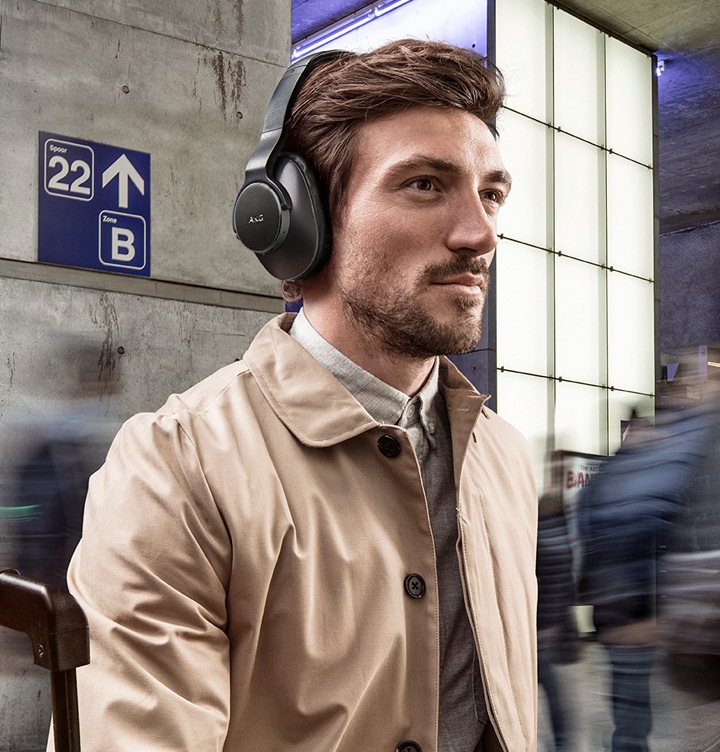 A man walking through a train station, wearing AKG N700NC M2 Wireless Headphones in black