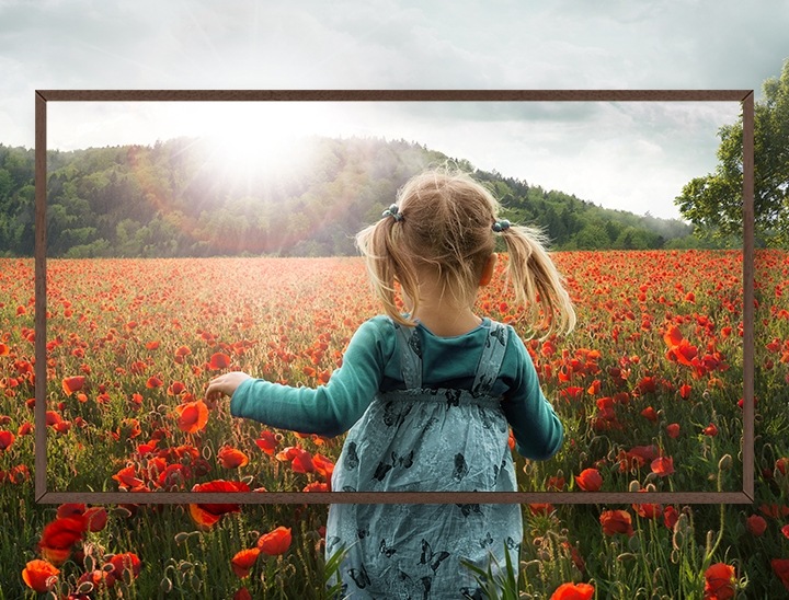 The back of a young girl walking in a field of flowers framed by the bezel.