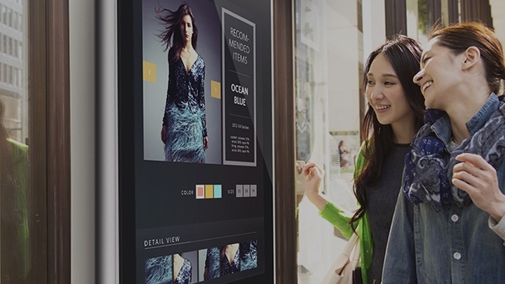 Deux femmes regardant les menus sur un panneau d'affichage extérieur Samsung placé à l'extérieur du restaurant