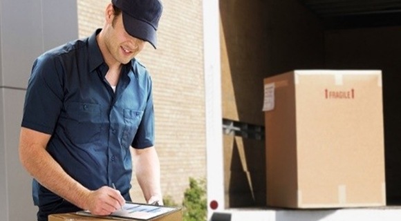 Un facteur signant à côté de son camion alors qu'il termine de livrer un colis