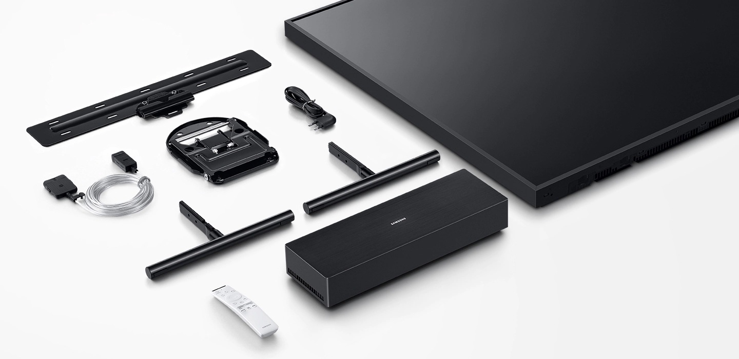 Le téléviseur The Frame et ses divers accessoires, incluant l’écran, le support télé, la fixation murale sans espace, la connexion invisible, le câble d’alimentation, la boîte One Connect et la télécommande unique sont disposés sur une surface blanche plate.