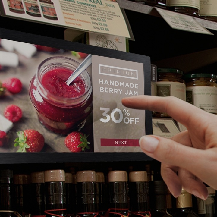 Ein Finger auf einem Samsung Signage-Bildschirm, der Details zu dem nebenstehenden Produkt anzeigt
