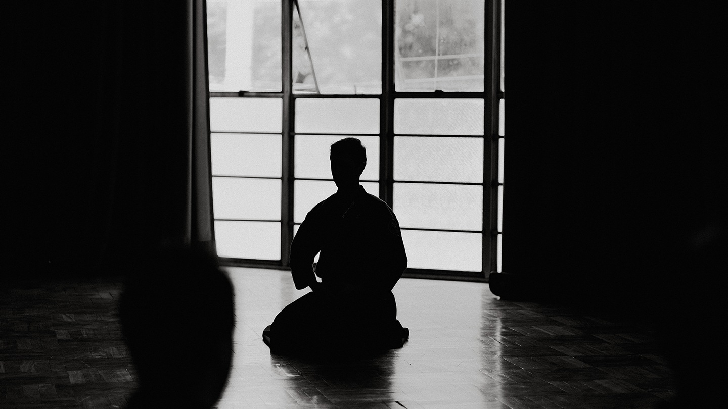 Zen-Meister in einem dunkeln Raum mit Gegenlicht.