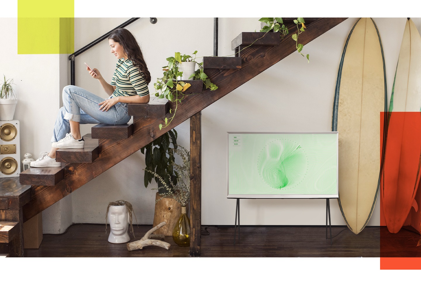 Perfekte Harmonie foto 5 Ein weisser Serif TV wird auf einem Standfuss neben einer Treppe gezeigt, auf der eine Frau mit ihrem Smartphone spielt. Auf dem Serif ist der Ambient Mode mit Blatt-Hintergrund zu sehen.