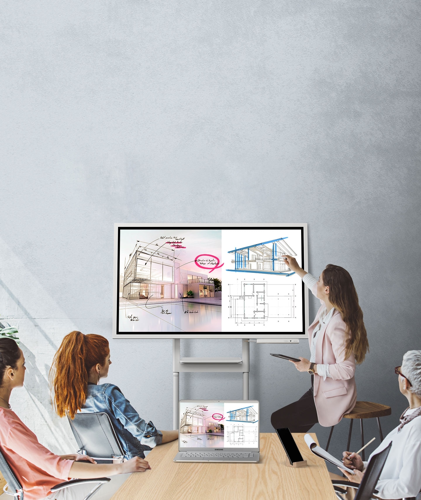 Una imagen que muestra cuatro personas en una reunión donde el dispositivo de Samsung Flip y un computador están conectados, mostrando las mismas imágenes. Están mirando la pantalla del Samsung Flip en modo horizontal y dos de ellos están tomando notas.