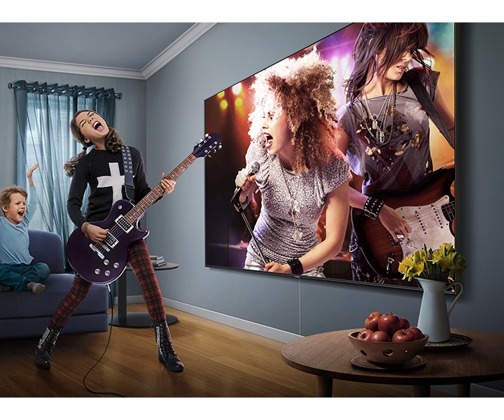 Záber na mladé dievča, ktoré v obývačke hrá na gitaru. Medzitým na superveľkej Samsung TV prebieha rockový koncert. Členovia rodiny nadšene skandujú a tlieskajú.