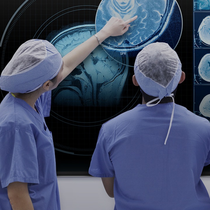 Eine Gruppe von Ärzten, die auf einem Samsung Smart Signage-TV ein CT-Bild analysieren