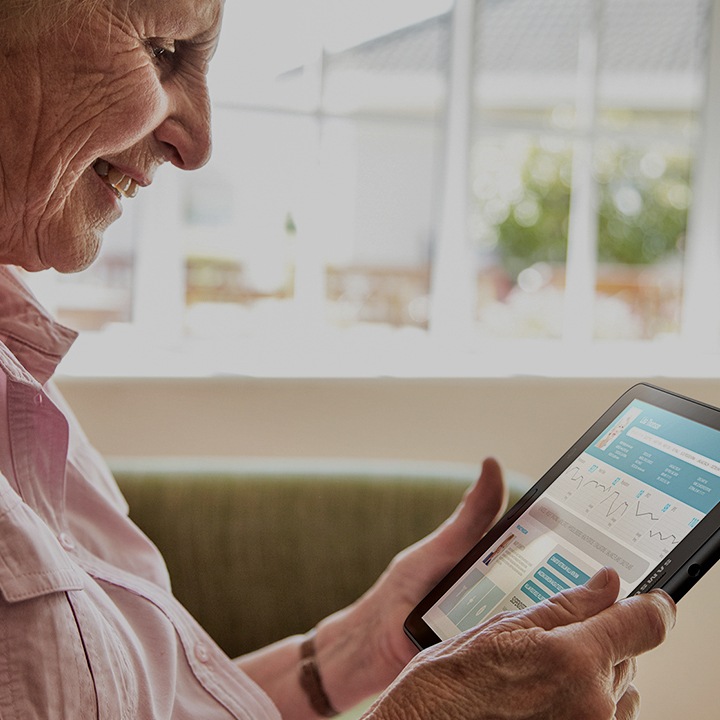 Eine Seniorin, die ein Samsung Tablet in der Hand hält und Gesundheitsinformationen nachliest