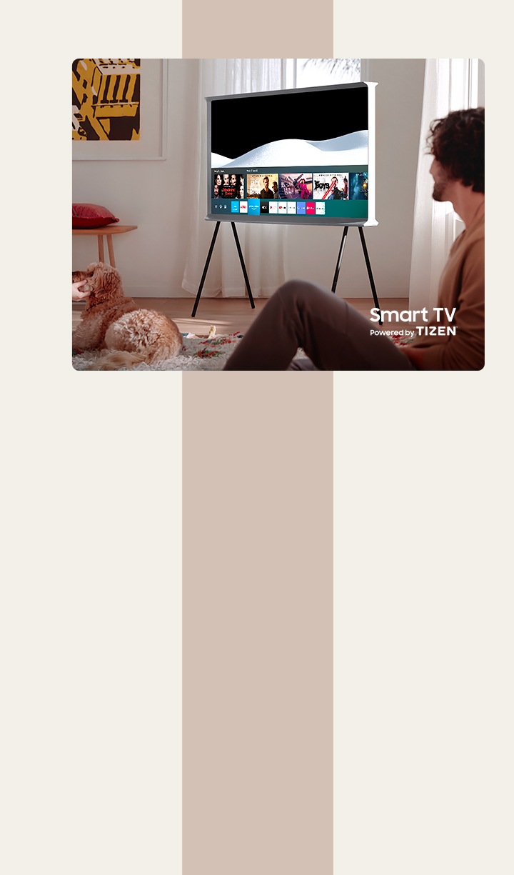 Ein Mann genießt die gemeinsame Zeit in einem Wohnzimmer. Ein The Serif in Cloud White ist in der Mitte des Raumes mit dem Samsung Smart Hub auf dem Display zu sehen. The Serif ist ein Smart TV mit einem Betriebssystem von Tizen.