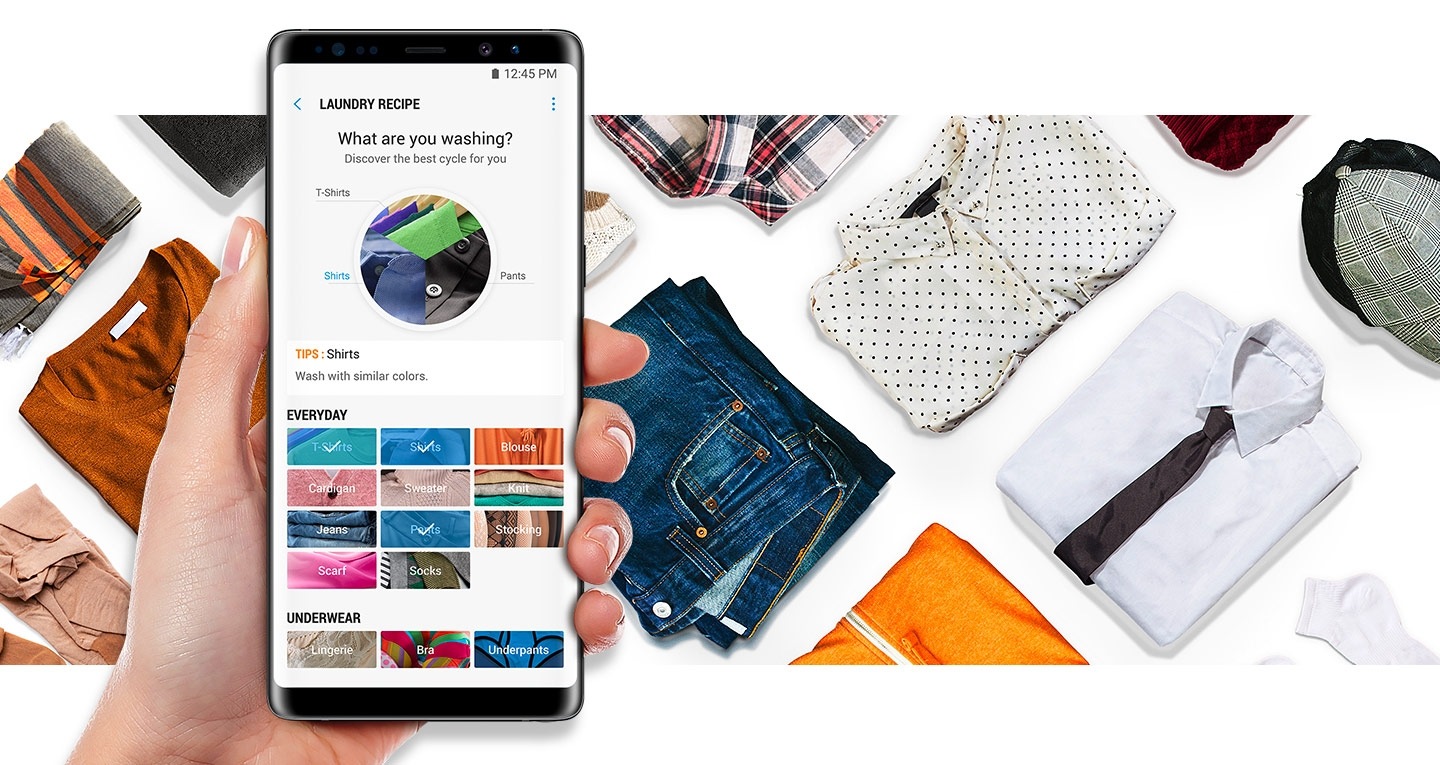 An image showing a smartphone, being held in one hand, running the Samsung Connect App. In the background, a selection of laundry, folded neatly, can also be seen.