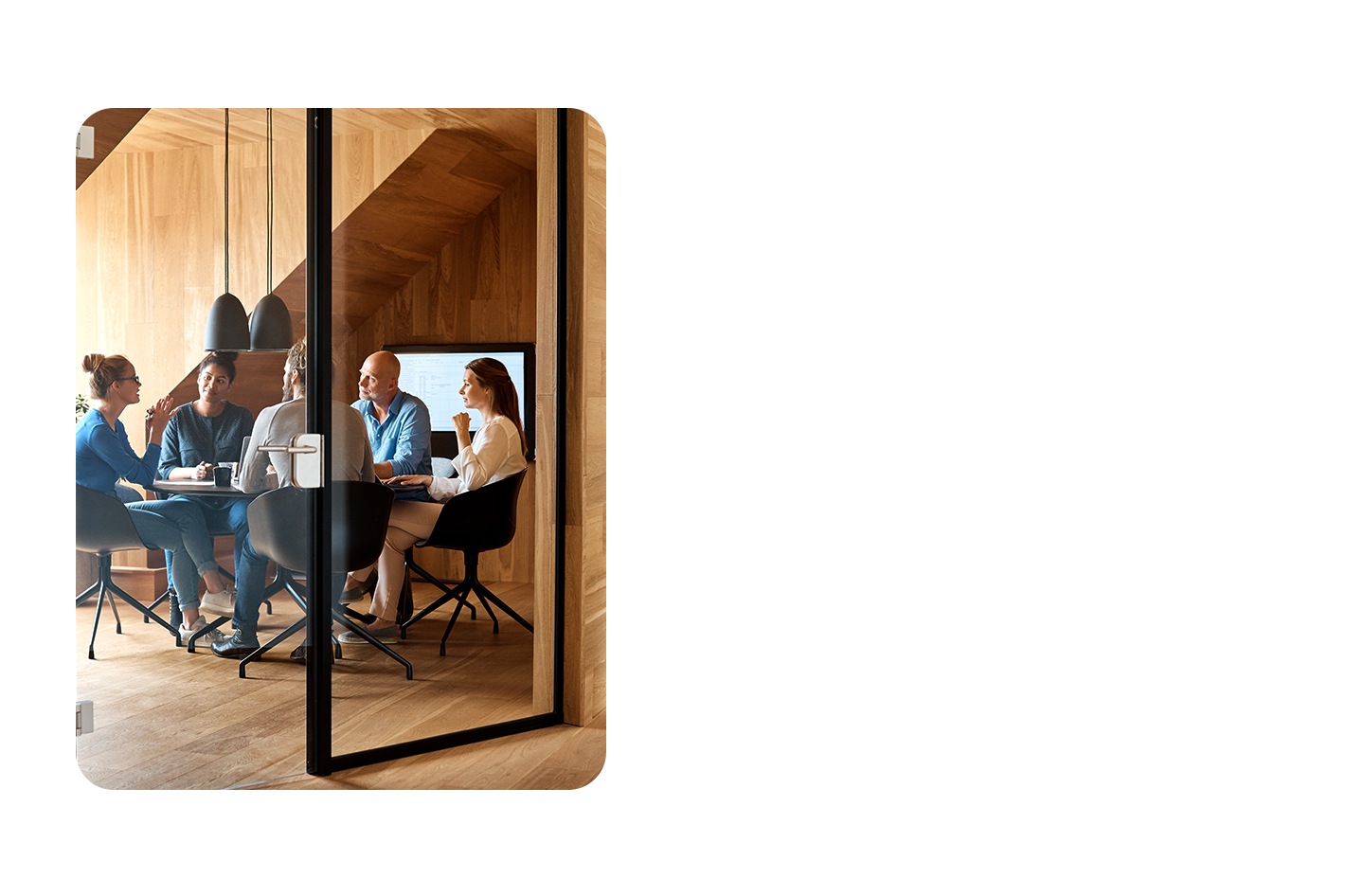 Os colegas de trabalho encontram-se numa mesa, num escritório minimalista em madeira.