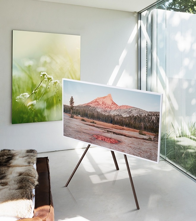 The Frame displaying a photo with no matte in the corner of a room away from the wall and window and placed on a white studio stand.