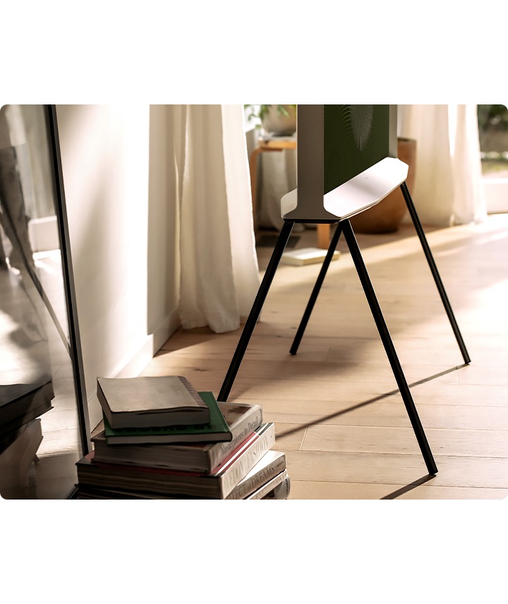 La mitad inferior de un modelo Cloud White de The Serif se muestra de lado en un soporte negro en una sala de estar ordenada, con libros en primer plano.