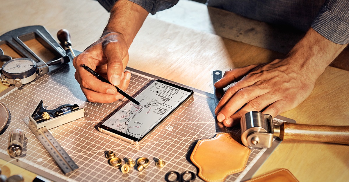 homme sur son smartphone et un plan de travail architecte