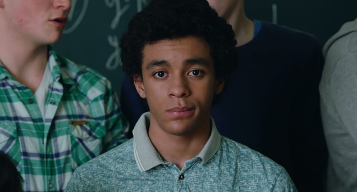 A male student standing surrounded by classmates