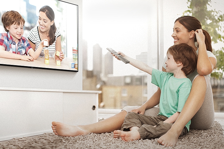 2 people are watching photos on Smart TV; the boy is controling the One Remote Control.
