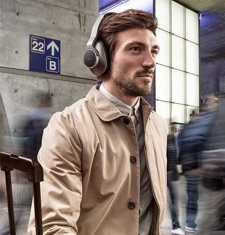 AKG Headphones Ένας άντρας που κάθετε σε έναν χώρο αναμονής με κόσμο, φορώντας τα ακουστικά AK