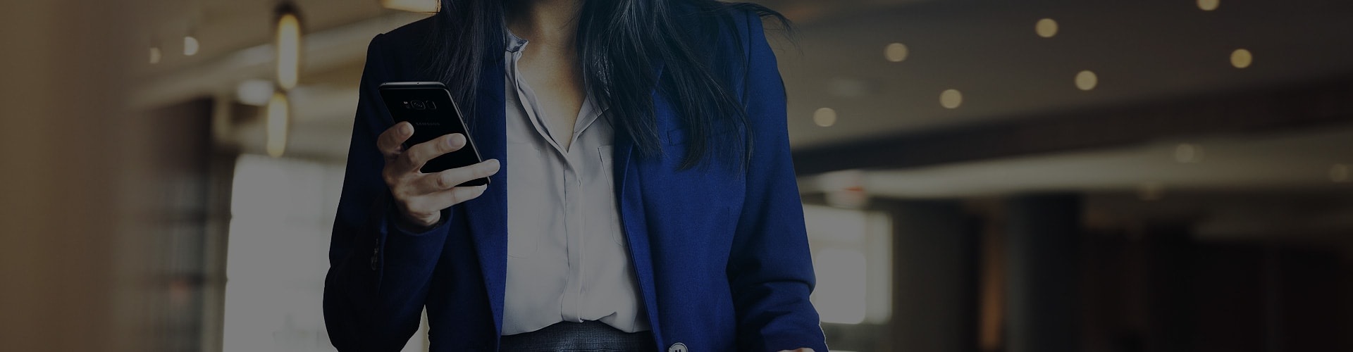 Woman wearing business suit holding Galaxy S8 in one hand