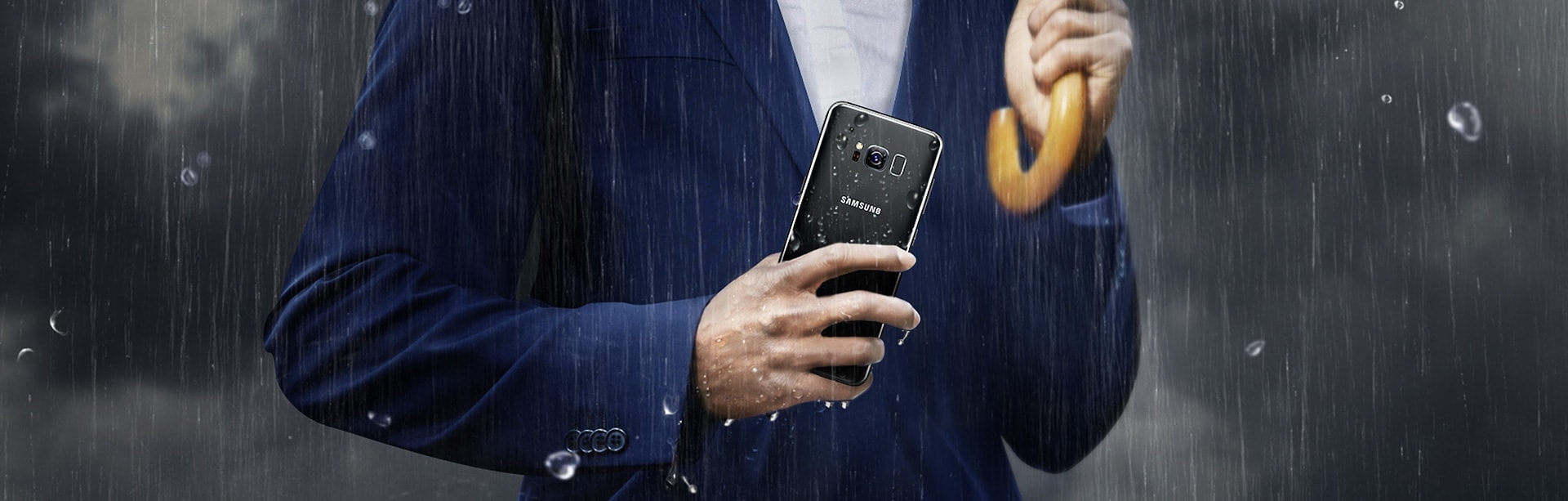 Man in business suit holding the Galaxy S8 in the rain