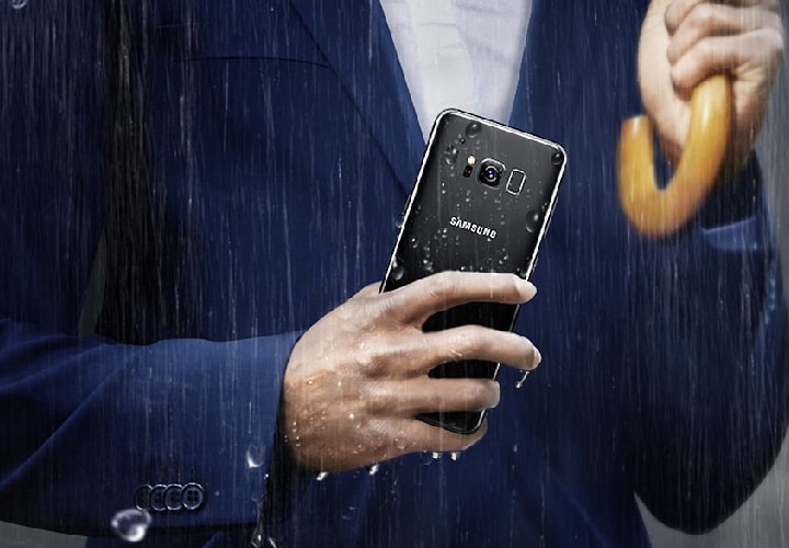 Man in business suit holding the Galaxy S8 in the rain