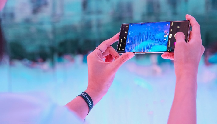 Galaxy S10 screen featuring a person standing in a mirror room filled with colorful visual displays.