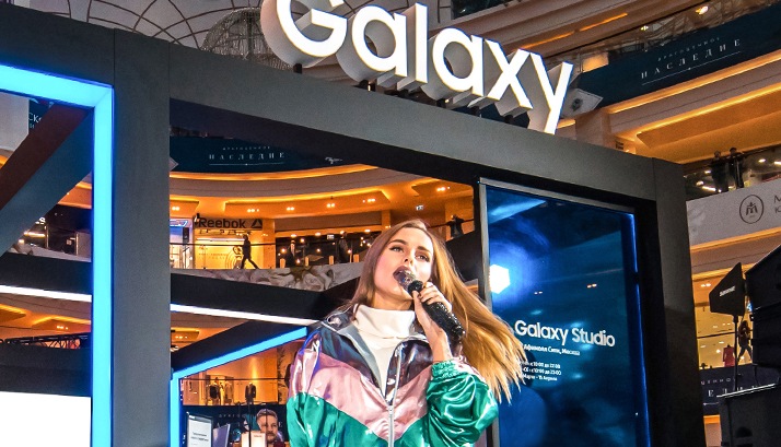 A female singer performs on stage at the Galaxy Studio booth.