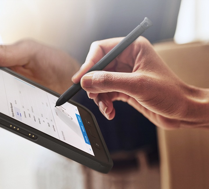 A woman signing on a digital receipt handed over by a man holding a box