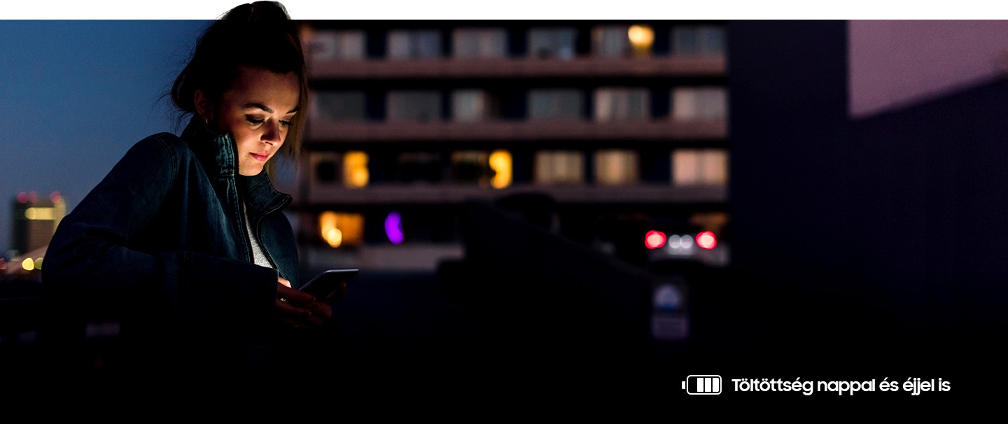 A telefonját este a szabadban használó nő képe. A jobboldalt alul látható akkumulátor ikon azt jelzi, hogy az akkumulátor még csaknem teljesen töltött állapotban van.