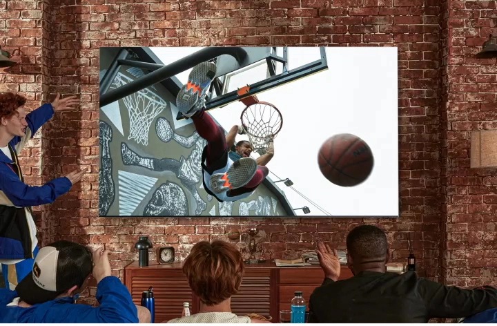 sport feature videó Egy epikus dunk jelenet jelenik meg a nagyképernyős TV-n, QLED 8K. Baráti társaság élvezi a sportvideót a nappaliban.