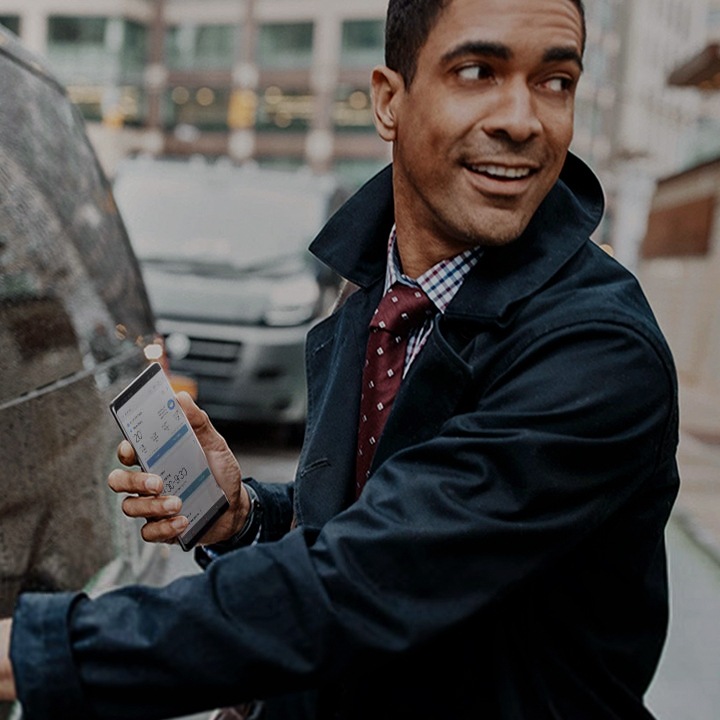 A man holding his Samsung smartphone while he is getting in the car