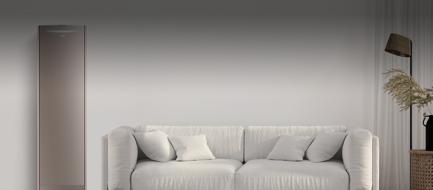 Un salotto con un divano bianco al centro, una lampada e una pianta sulla destra e un climatizzatore smart sulla sinistra.