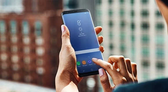 Una donna che tocca lo schermo di uno smartphone Samsung per trasferire contenuti mentre non è in ufficio