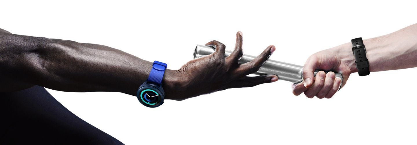 Braccio che indossa Gear Sport blu atto a prendere la staffetta da un altro braccio che indossa Gear Sport nero