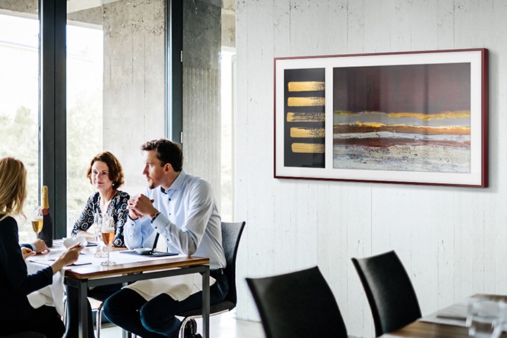 People are sitting at the table having a conversation while The Frame in Art Mode hangs on the wall