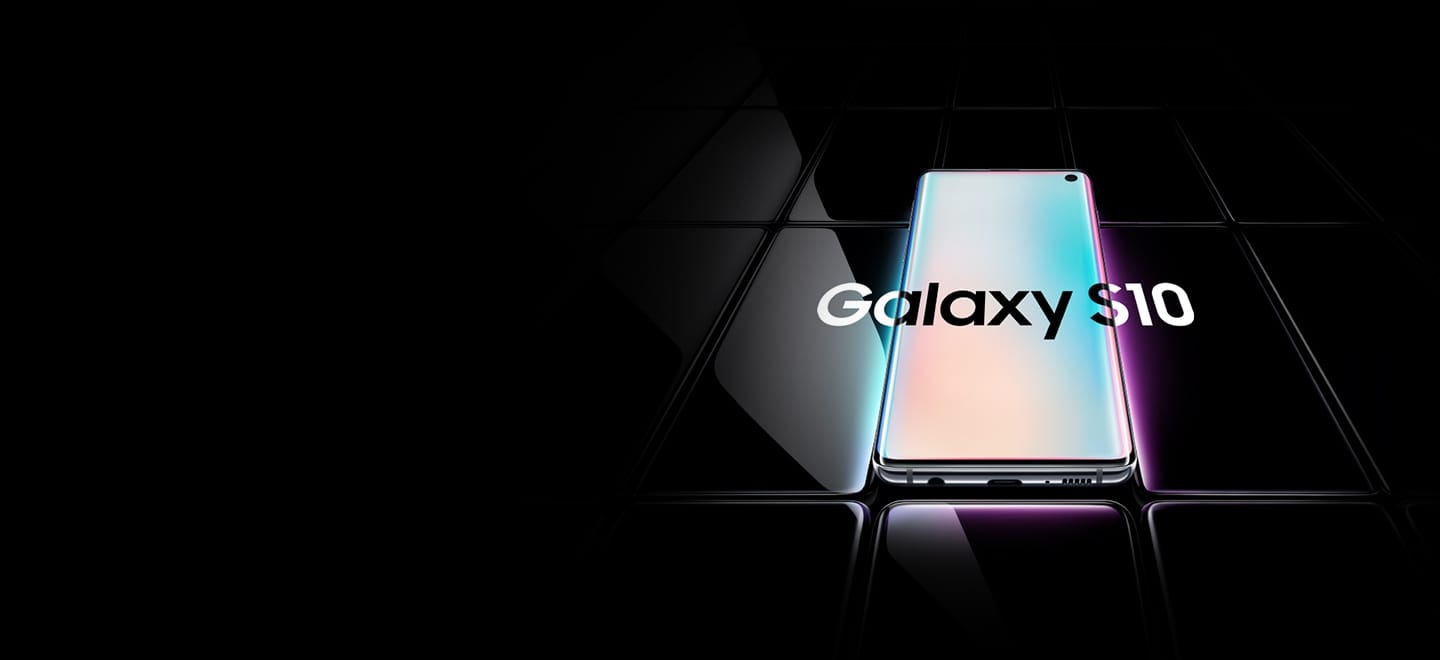 Several Galaxy S10 plus phones all laid flat and seen at an angle from the bottom. All are black except the one in the middle, which is shown with a prismatic gradient onscreen with Galaxy S10 plus overlaid on top of it and the two phones on either side.