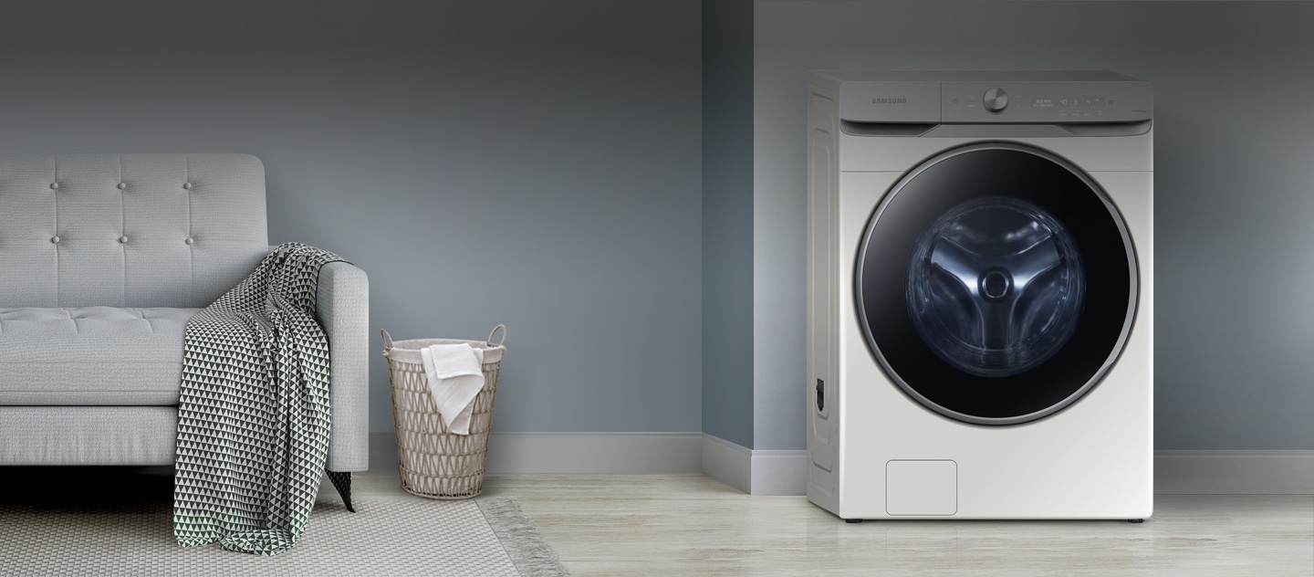 A smart washing machine on the right hand side and a sofa, laundry basket, and some laundry that needs to be washed are on the left hand side.