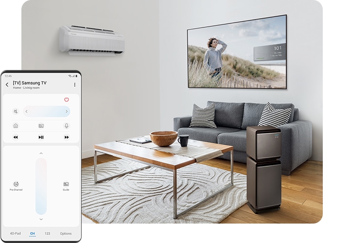 A living room with an air conditioner on wall and two Cube Air Purifiers stacked next to the coffee table in the center of the room. A sofa is behind the coffee table and above the sofa is a 65-inch Q7 QLED TV attached to the wall. On the left side foreground, a Galaxy screen shows a mobile remote control of the smart TV.