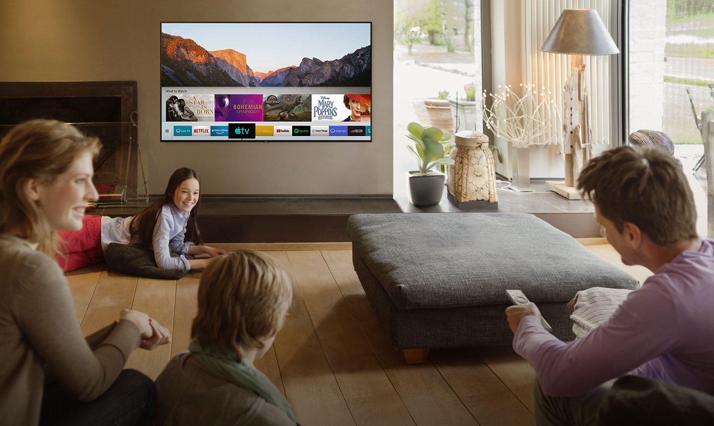 People are watching Smart TV in the living room and Smart Hub UI is displayed over a nature background image on TV screen