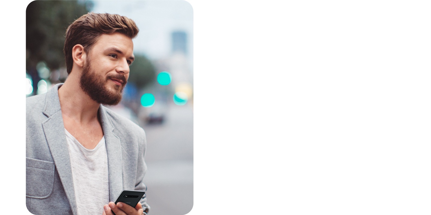 نرى رجلًا يحمل هاتفًا أثناء عبور شارع مزدحم بالمدينة.
