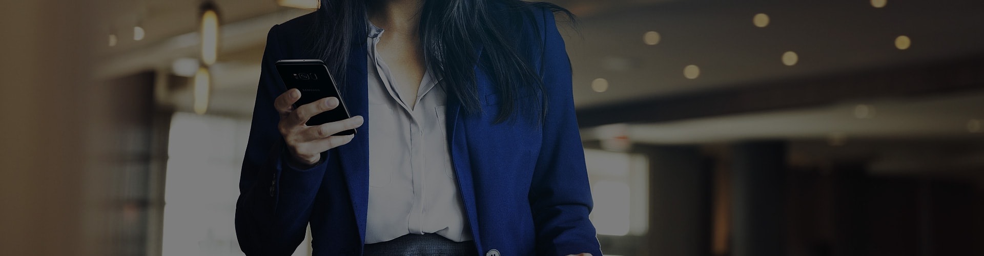 Woman wearing business suit holding Galaxy S8 in one hand