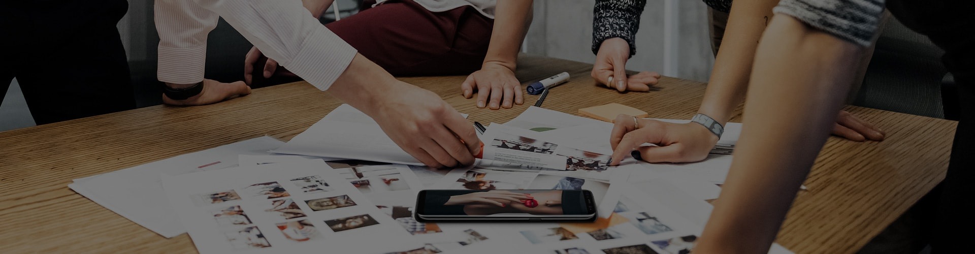 Hands on table showing people having a meeting with the Galaxy S8 and documents on the table