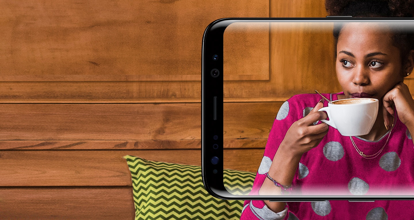 „Samsung Galaxy S8“ ekrane matoma kavinėje kavą gurkšnojanti moteris