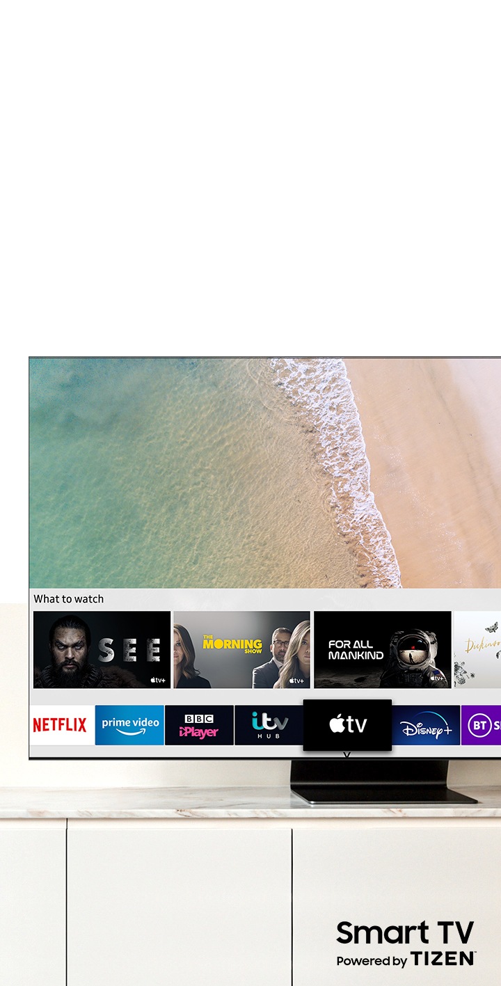 Samsung QLED televizora ekrānā redzams Smart Hub, Samsung Smart TV platformu. Zem televizora redzams “Smart TV, kuru darbina TIZEN” logotips