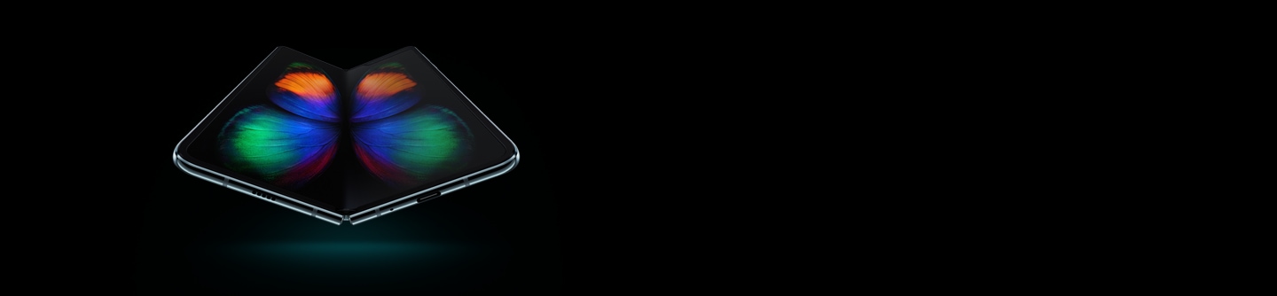 Galaxy Fold in Space Silver seen at a slight angle from the bottom, unfolded, with a multicolor butterfly graphic on-screen.